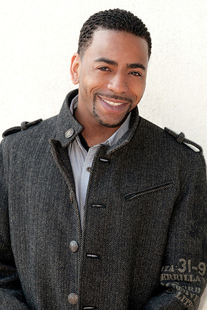 Professional portrait of a smiling man wearing a charcoal jacket over a collared shirt.