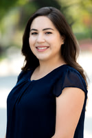 Professional outdoor headshot of a smiling woman in a navy top.