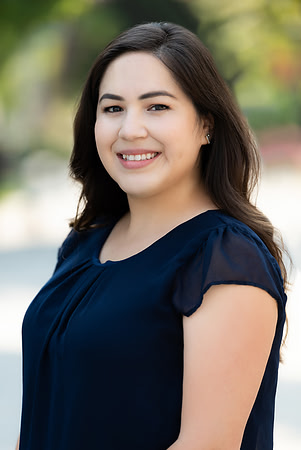 Professional outdoor headshot of a smiling woman in a navy top.