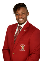 Studio portrait of a young man wearing a red academic or organization blazer against white.