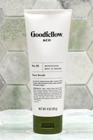 Product photograph of a Goodfellow & Co face scrub tube standing against pale geometric tile.