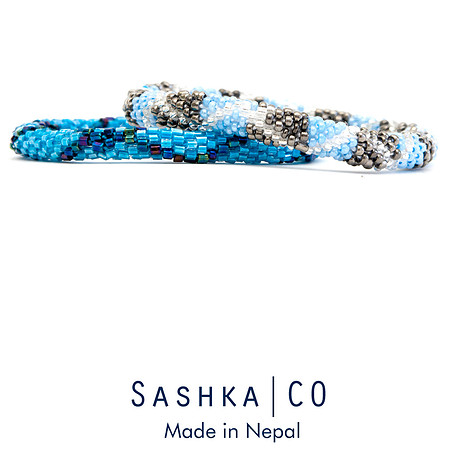 Product photograph of blue, white, and metallic beaded bracelets on a white background with Sashka Co branding.