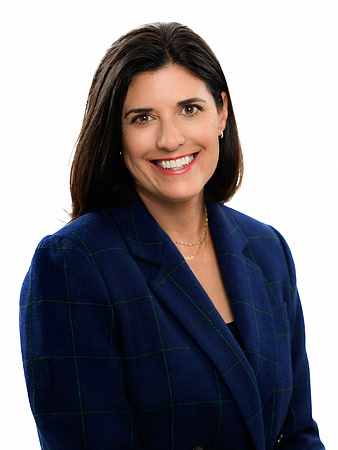 Clean studio business headshot of a woman in a dark blue blazer against a white background.
