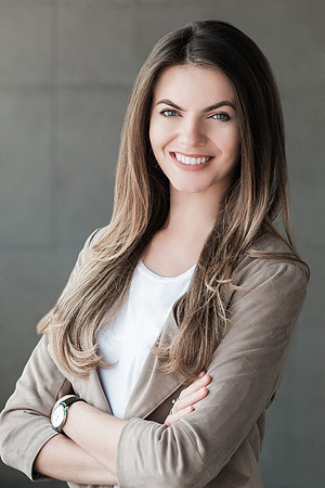 Professional portrait of a woman in a light jacket over a white top with arms crossed.