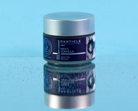 Skincare product photograph of a Particle men’s face mask jar on a reflective blue surface.