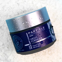Close-up skincare product image of a Particle face mask jar covered with water droplets on a light textured surface.