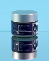Skincare product photograph of a Particle men’s face mask jar on a wet reflective blue surface.
